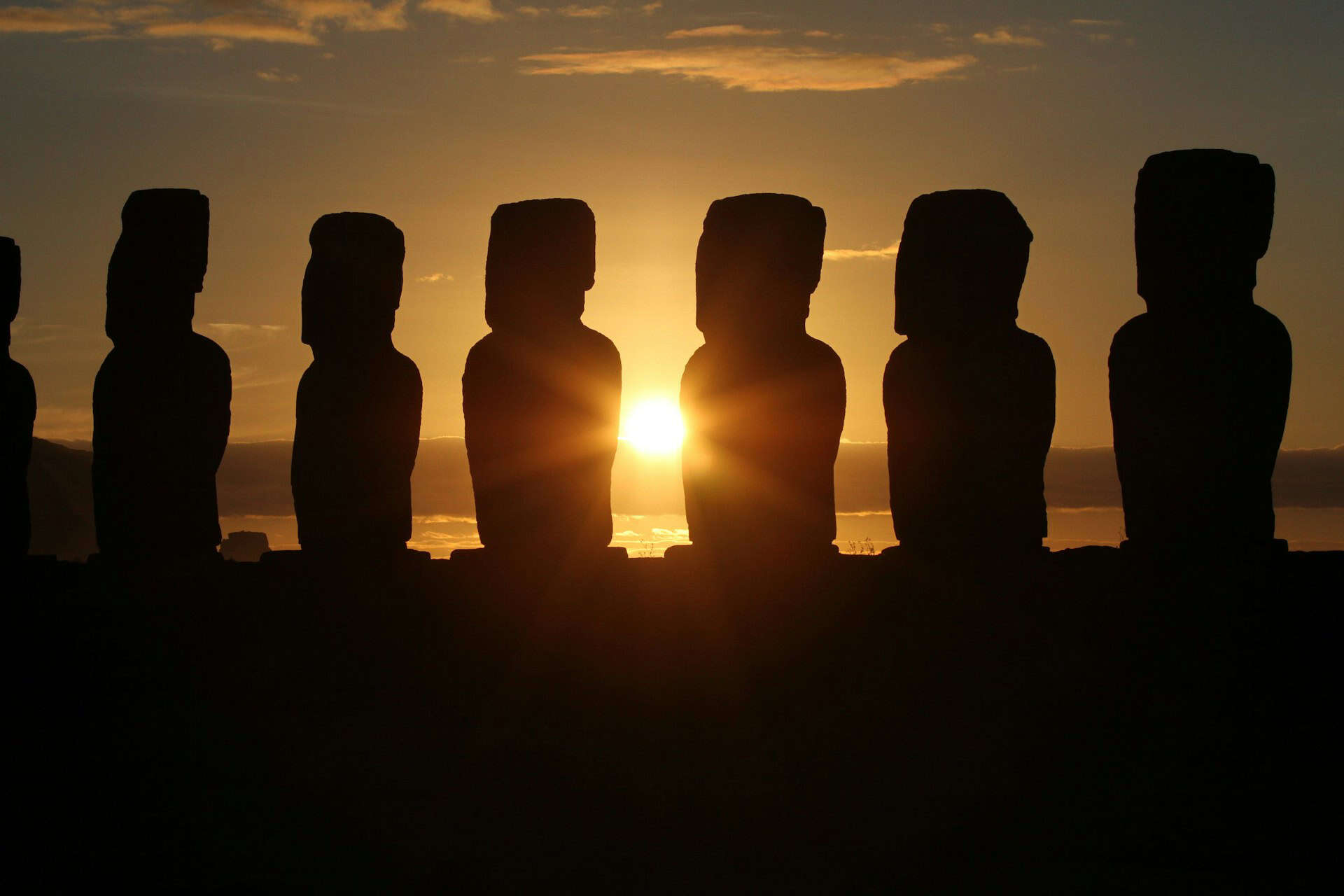 Ancient statues in front of a sunset.